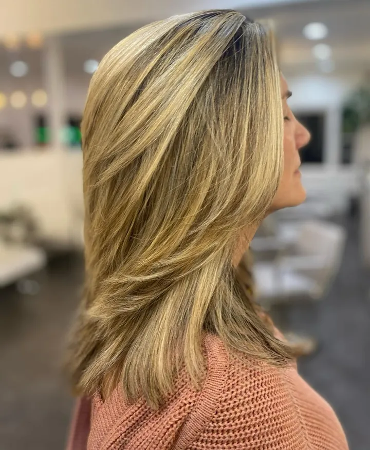 Shoulder-length layered hair with golden blonde highlights, seen in profile.